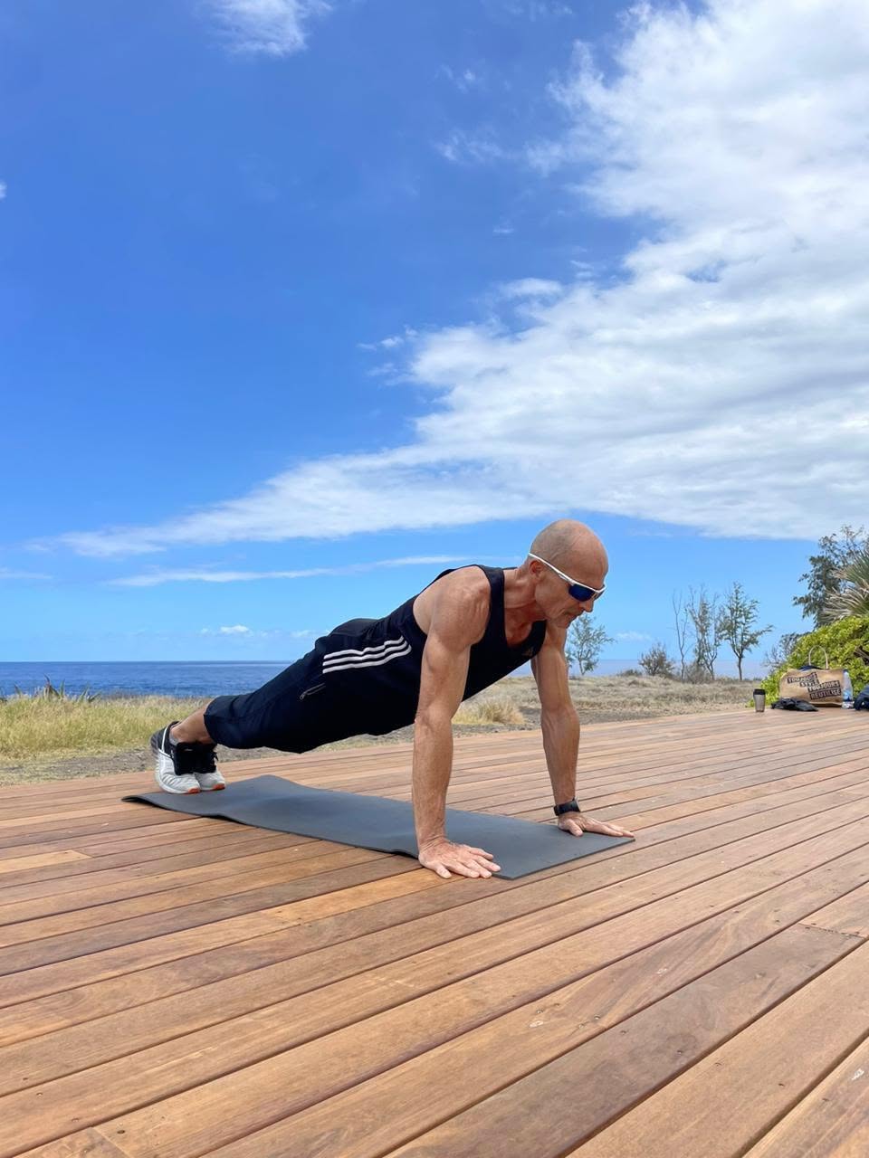 John en gainage face à l'océan, sur une terrasse en bois à La Réunion